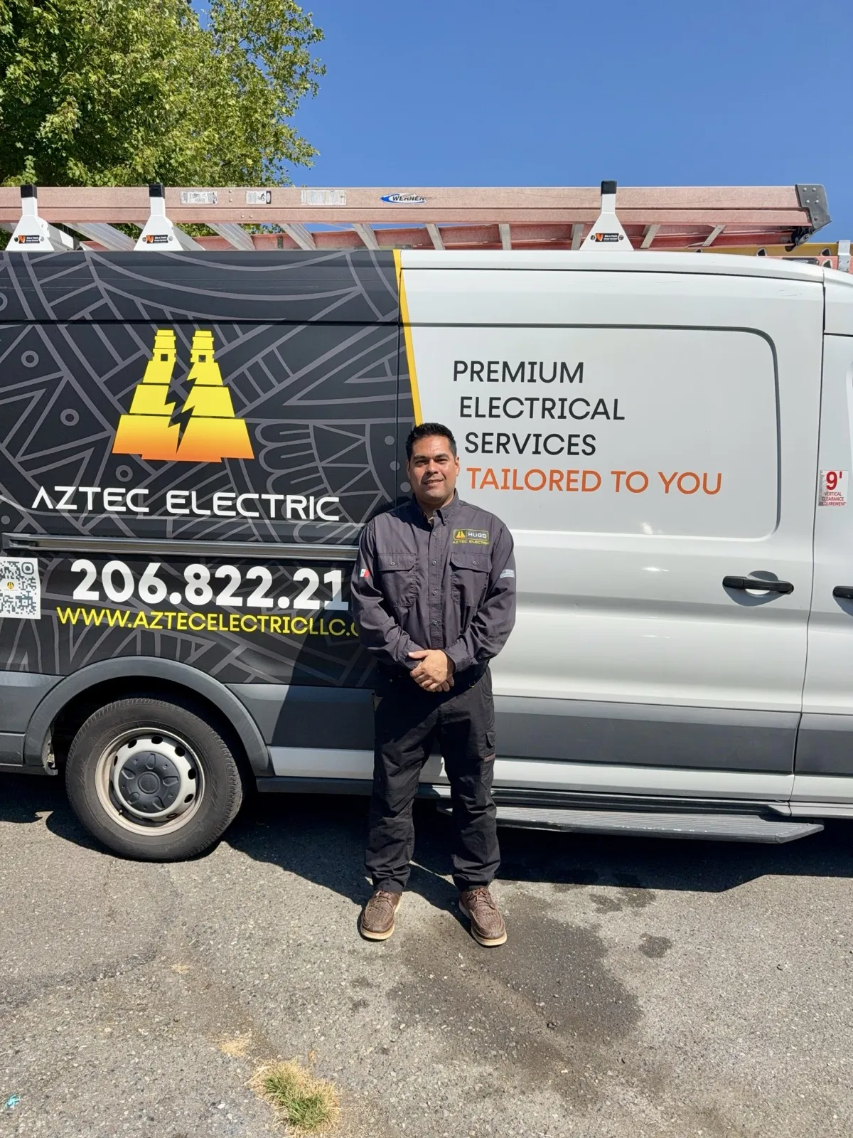 Hugo, owner of Aztec Electric LLC, standing with the fully wrapped service van